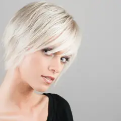 Mujer con rubio platino y capas cortes de pelo media melena modernos. Suavemente inclinada, mira a la cámara.