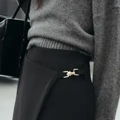 Chaqueta gris y bolso negro sobre falda negra larga con detalle dorado. Un look elegante para saber como combinar una falda negra larga.