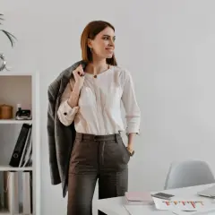 Mujer con un elegante outfit oficina: camisa blanca, pantalón gris y chaqueta a cuadros.