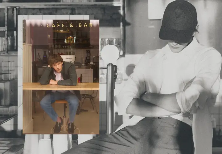 Un joven con un armario cápsula hombre, sentado en un café, reflexiona.