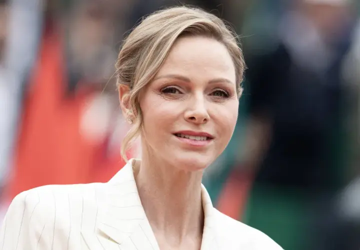 La princesa de Mónaco, Charlene Wittstock, sonríe con un traje blanco a rayas.