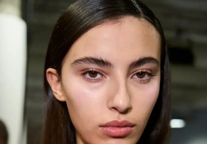 Primer plano de una joven con cejas pobladas y mirada intensa. Su piel luce natural y sus labios están ligeramente brillantes.