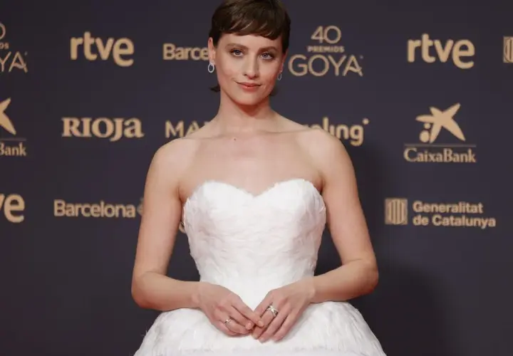 Una actriz posa en la goya alfombra roja con un vestido blanco voluminoso.