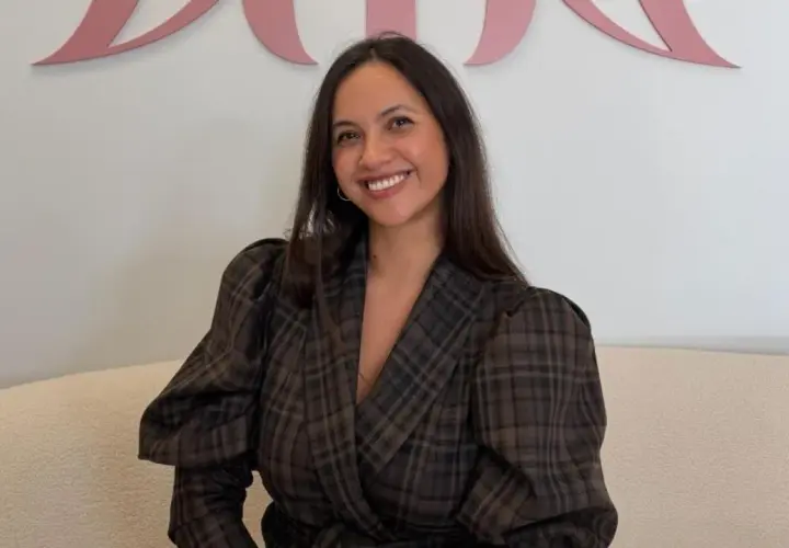 Sonriendo, una mujer con un blazer de cuadros marrones y mangas abullonadas. Sus opiniones sobre miphai son positivas.