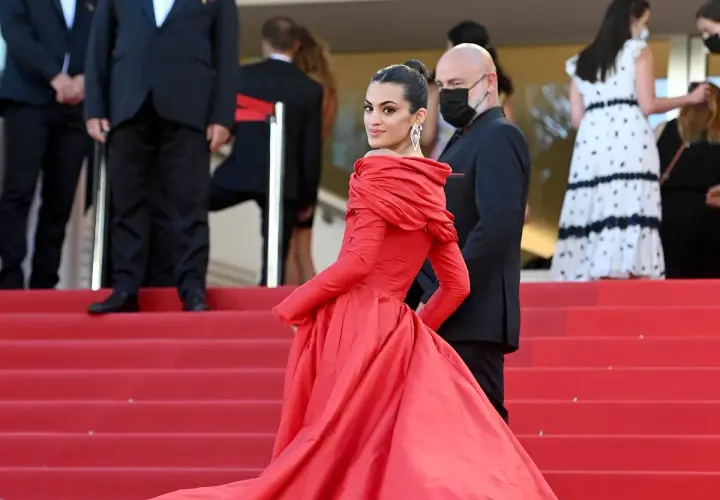 Una mujer luce un espectacular vestido rojo en la alfombra, demostrando cómo combinar un vestido rojo con elegancia y glamour.