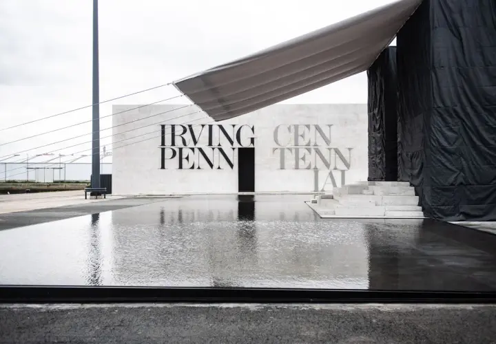 Reflejos en el agua de la entrada a la celebración del centenario de Irving Penn, con un toldo gris sobre la estructura.