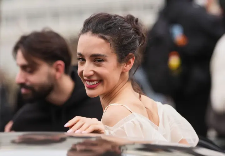 La belleza de Paula Badosa se refleja en su sonrisa radiante, con el cabello recogido y un vestido blanco delicado.