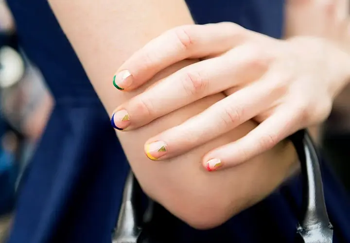 Manicura geométrica con colores vibrantes y detalles dorados en uñas cortas bonitas.