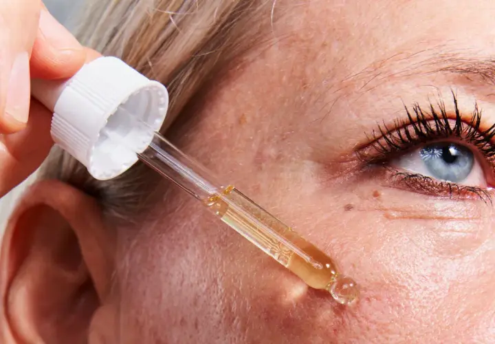 Una mano aplica un suero con un gotero sobre la piel. Descubre para qué sirve el retinol y cómo puede mejorar tu piel.