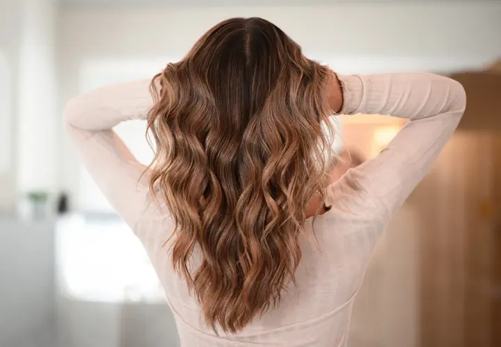 Melena castaña con ondas surferas, un estilo desenfadado y natural que realza la textura del cabello.