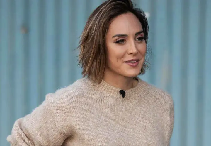 Mujer con un suéter beige y modernos cortes de pelo bob, con un fondo azul.