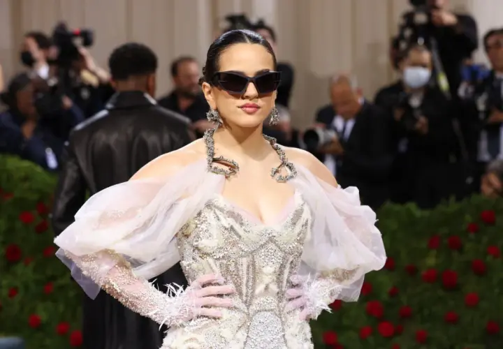 Rosalía deslumbrante en la Met Gala, con un vestido blanco adornado y gafas de sol audaces.