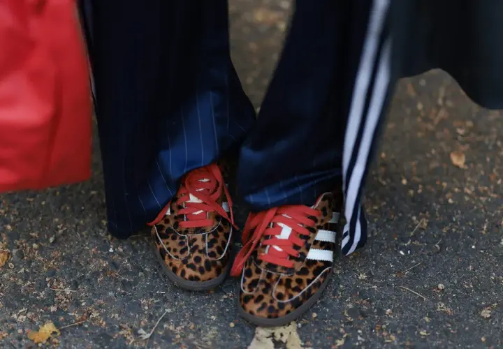 Zapatillas tendencia con estampado de leopardo y cordones rojos, combinadas con pantalones de raya diplomática.