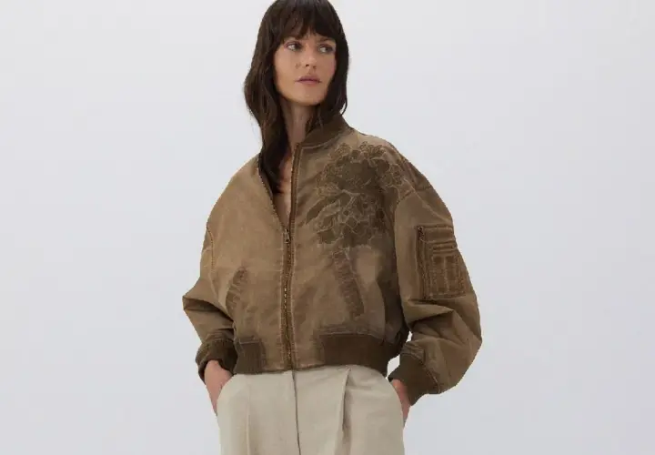 Mujer posando con una bomber marrón con bordado floral. Ideal para combinar bomber mujer con estilo casual.