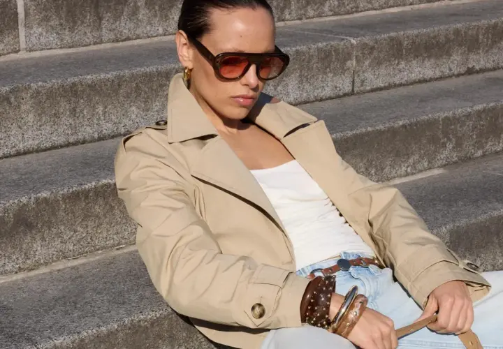 Mujer con gabardina beige y gafas de sol, lista para la moda primavera.