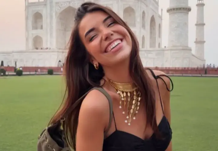 Elena Gortari sonríe feliz frente al Taj Mahal, luciendo un collar dorado y un vestido negro.