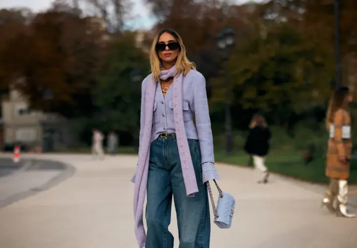Mujer con look elegante con vaqueros, chaqueta lila, bufanda y bolso a juego.
