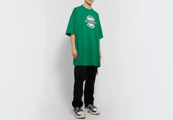 Camiseta verde de **oversize significado** con logo de Vetements, combinada con vaqueros negros rotos y zapatillas deportivas.