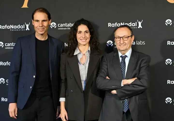 Rafael Nadal, Xisca Perelló y un hombre con traje posan ante un fondo con logos de la Fundación Rafa Nadal y Cantabria.