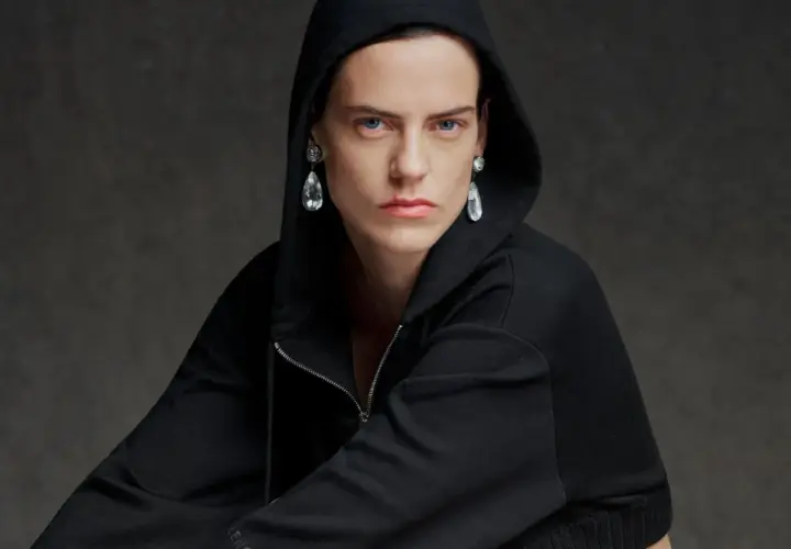 Modelo con sudadera negra con capucha y pendientes de lágrima, una visión audaz que evoca la estética de Pierpaolo Piccioli.