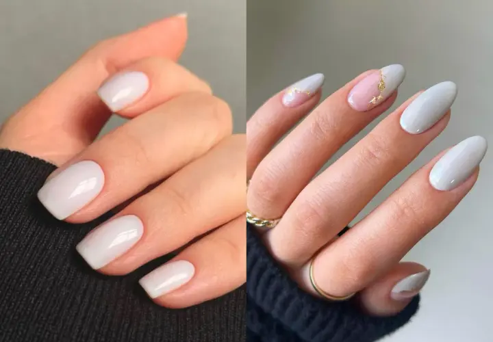 Manicura elegante con uñas blancas, algunas con detalles dorados y un toque de rosa pálido.