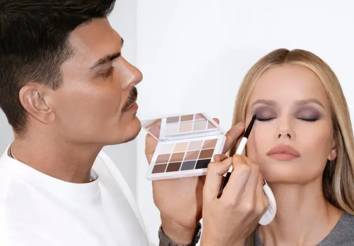 Mario Dedivanovic, maestro del maquillaje, aplica sombra de ojos a una modelo con una paleta neutra.