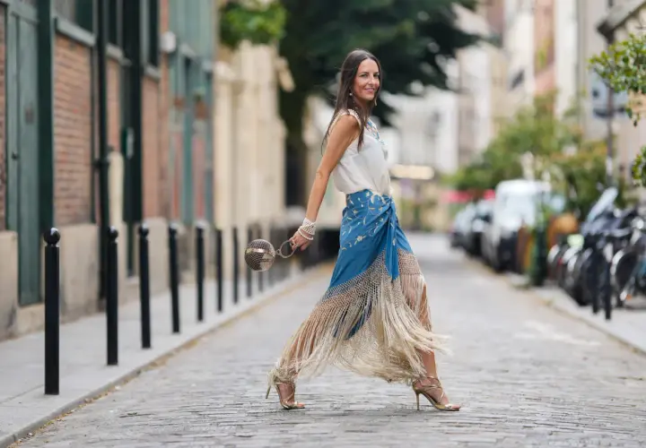 Mujer con falda larga azul con flecos y top blanco, perfecta ropa para ir a la feria de dia.