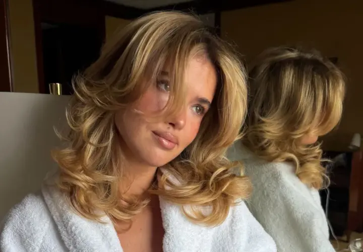 Chica con cabello rubio y rizado, luciendo unos cortes de pelo largo con capas voluminosas.