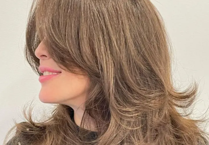 Cabello castaño con un corte mariposa, capas suaves que enmarcan el rostro y dan movimiento.
