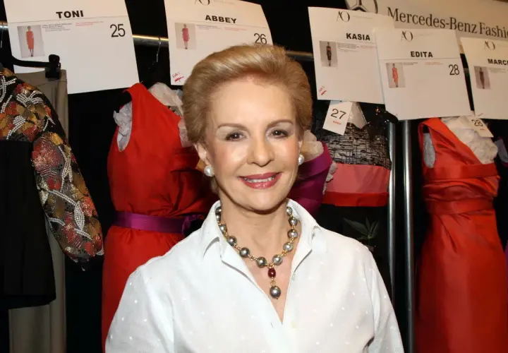 Carolina Herrera, icono de la moda, sonríe rodeada de vestidos de pasarela.
