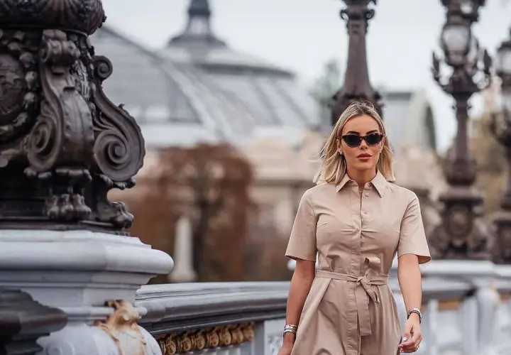 Alba Silva camina con elegancia por un puente parisino, luciendo un vestido camisero y gafas de sol.