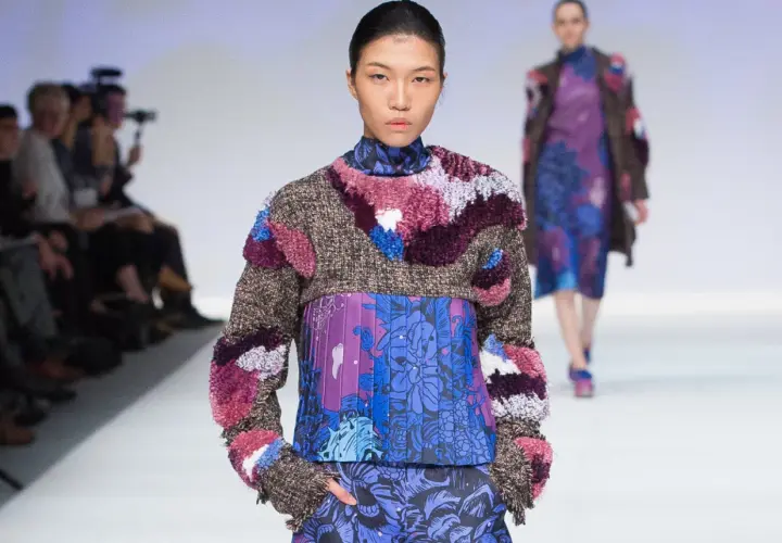 Modelo luce un diseño de upcycling que es una explosión de texturas y colores, con un suéter de tweed y apliques peludos sobre un vestido estampado floral.