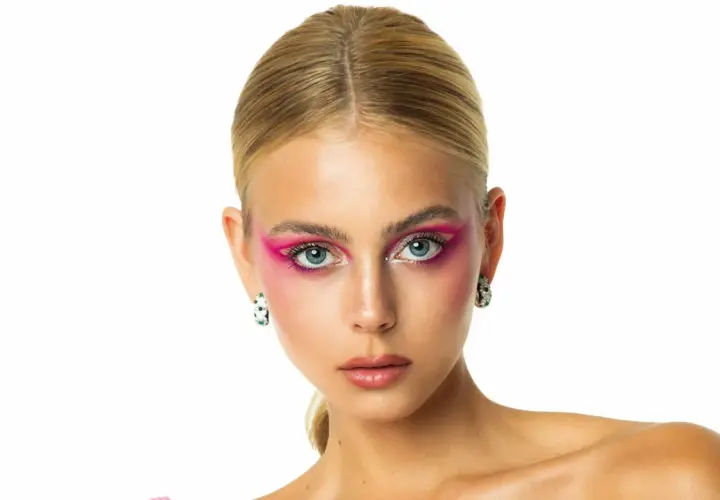 Mishel Gerzig con un audaz maquillaje de ojos rosa vibrante y pendientes llamativos.