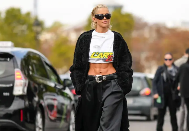 Mujeres bajitas con estilo urbano, abrigo negro, top corto y pantalones anchos.