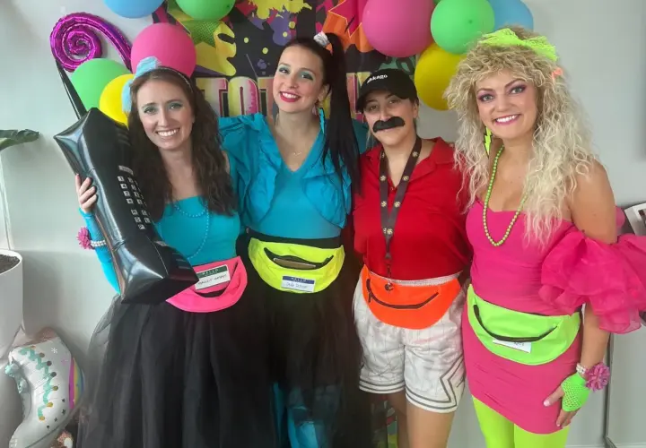 Cuatro amigas celebran una fiesta moda de los 80 con atuendos coloridos, riñoneras y peinados voluminosos.