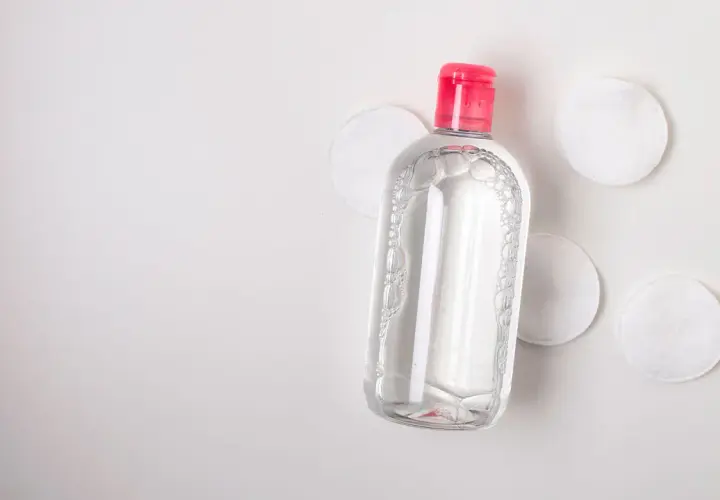Botella de agua micelar con tapa rosa y discos de algodón. Ideal para limpiar ante y rostro.