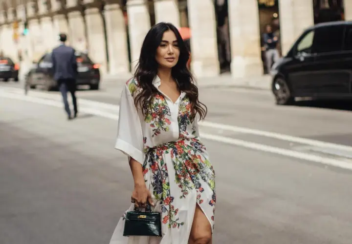 Mujer con vestido estampado floral, estilo manga francesa, pasea por París con un bolso verde.