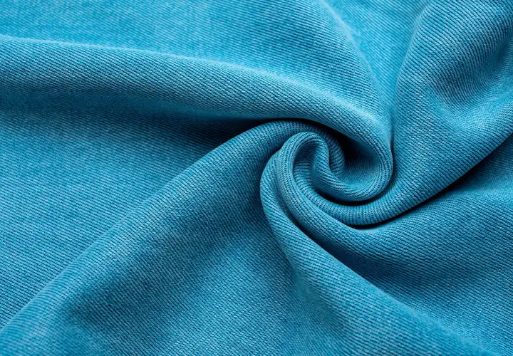 Textura de tela Tencel azul vibrante, suave y con caída, que evoca la comodidad y sostenibilidad de este tejido.