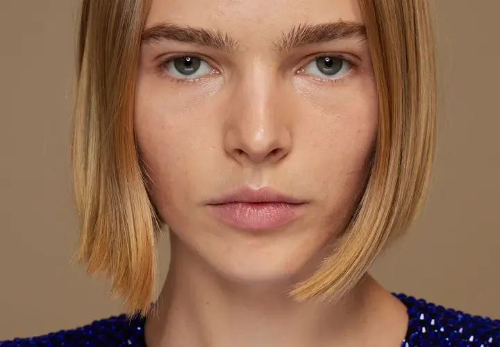Primer plano de una mujer con un corte bob rubio y un vestido azul brillante.