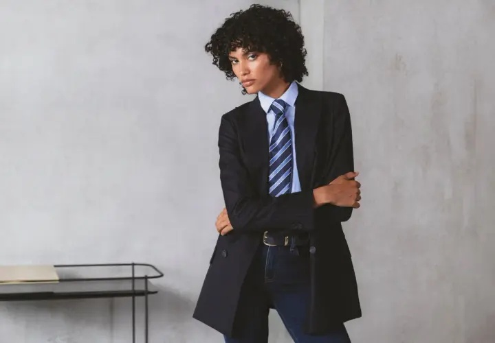 Persona andrógina con traje a rayas, camisa azul y corbata a juego.