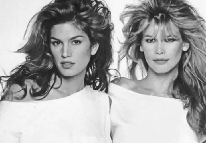 Dos icónicas modelos de los 90, Cindy Crawford y Claudia Schiffer, posan con sus melenas al viento y atuendos blancos.