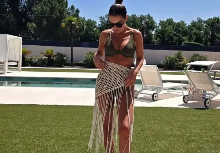 Paula Echevarría luce un bikini verde y una falda de crochet con flecos junto a la piscina, disfrutando del sol.