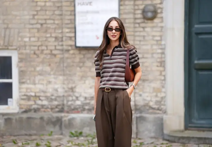 Mujer con estilo, combinando un pantalón marrón de tiro alto con una blusa a rayas marrones y blancas.
