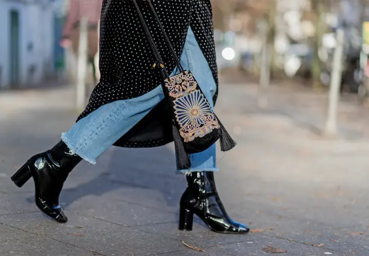 Estilo urbano: cómo combinar botines negros brillantes con jeans desgastados y un bolso bordado.