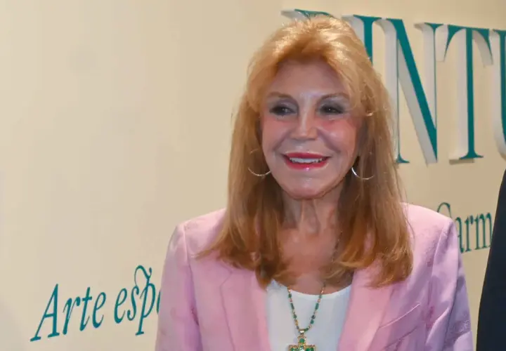 Tita Thyssen, con su icónico estilo, sonríe luciendo un blazer rosa y un collar llamativo.