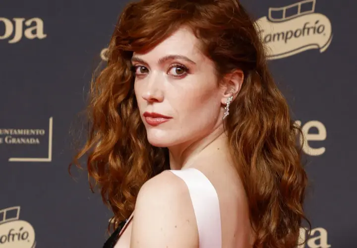 Itsaso Arana, con su cabello pelirrojo ondulado y un vestido rosa, posa con elegancia.