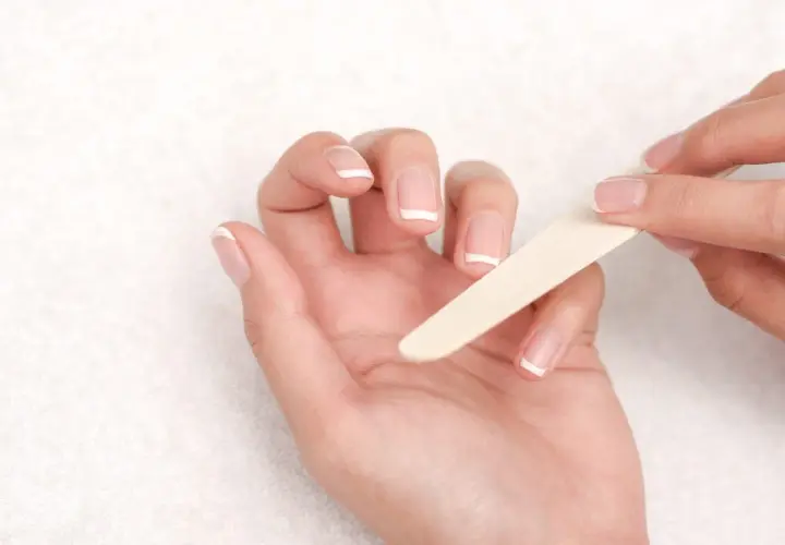 Manos limándose las uñas francesas. Una guía visual para saber como quitar uñas de gel.