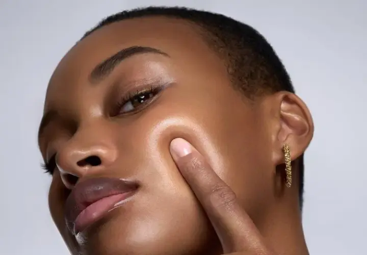 Piel oscura con un brillo dewy, resaltando sus pómulos y labios.