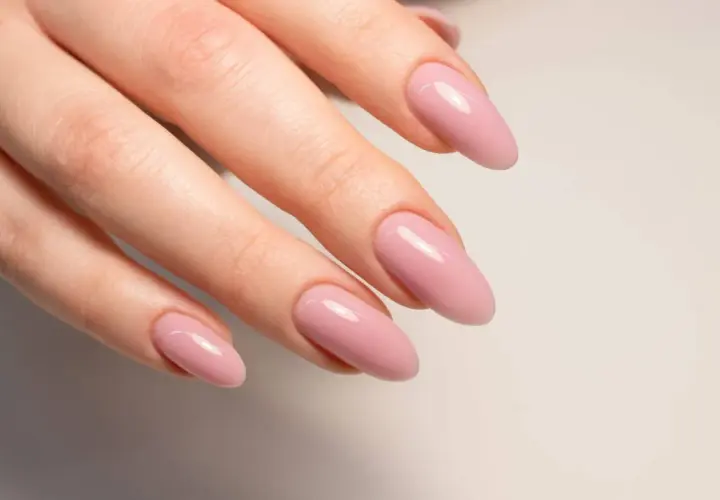 Manicura con uñas semipermanentes naturales en tono rosa pálido, con forma almendrada y acabado brillante.