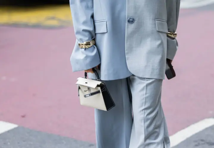 Traje gris con pantalones de pierna ancha (wide leg significado) y bolso blanco y negro.
